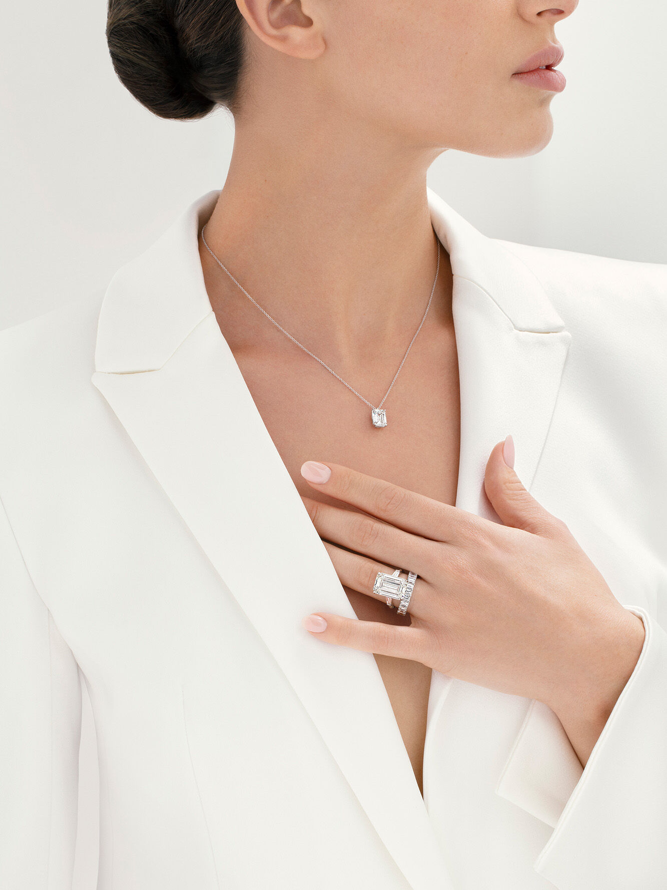 Image shows models wearing emerald cut diamond necklace and engagement ring