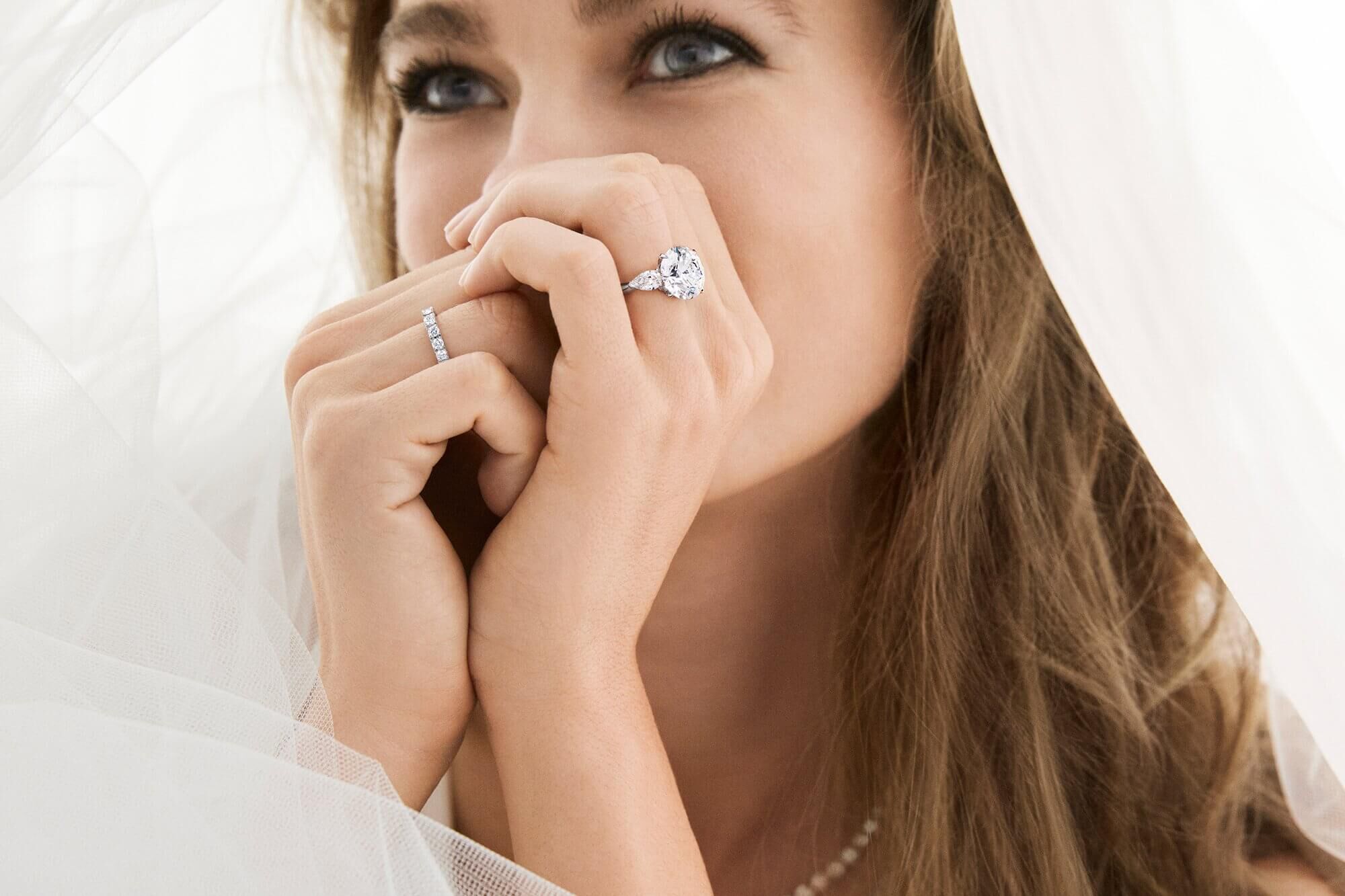Model bride wears Promise Round Diamond Engagement Ring with pear shaped side stones and Castle Set Round Diamond Wedding Band from the Graff bridal collection.