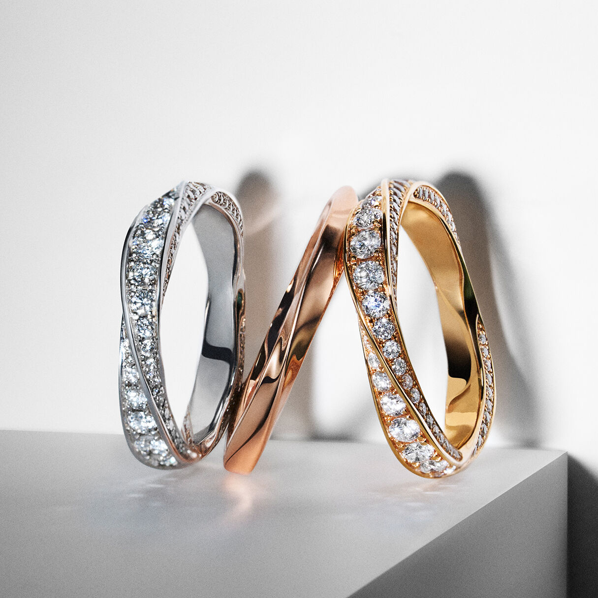 Still life image shows Graff white diamond white gold, rose gold and yellow gold spiral rings 