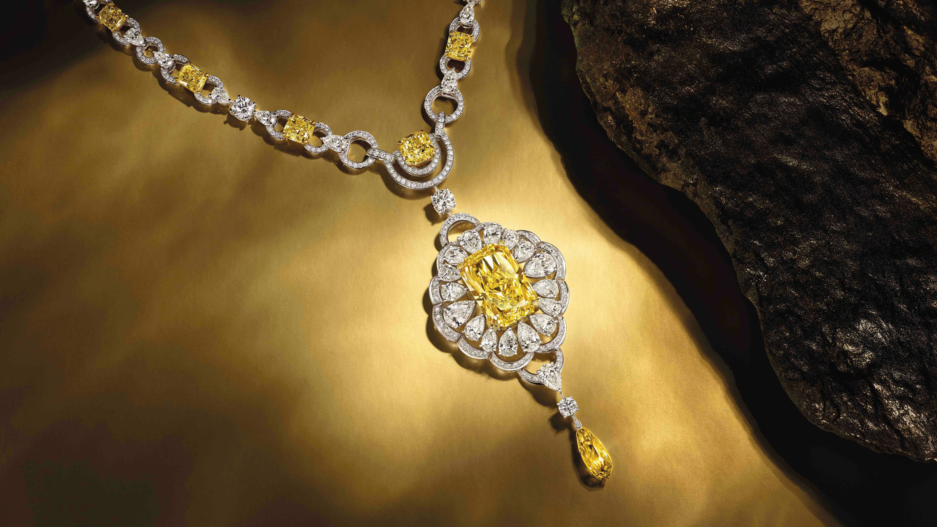 A Graff yellow and white diamond high jewellery necklace next to a rock