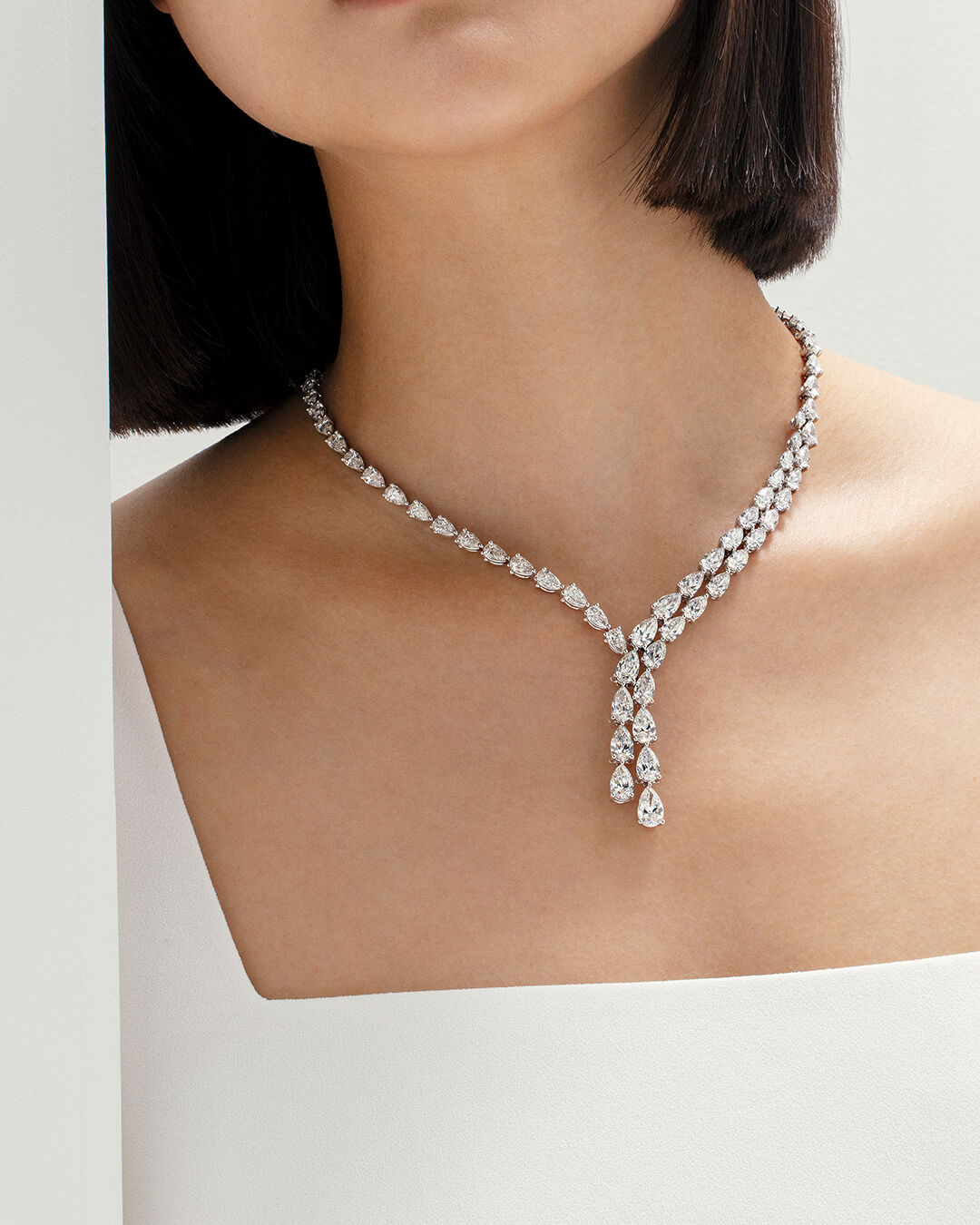 Classic Graff - image shows model hand wearing Emerald cut diamond necklace, eternity ring and engagement ring