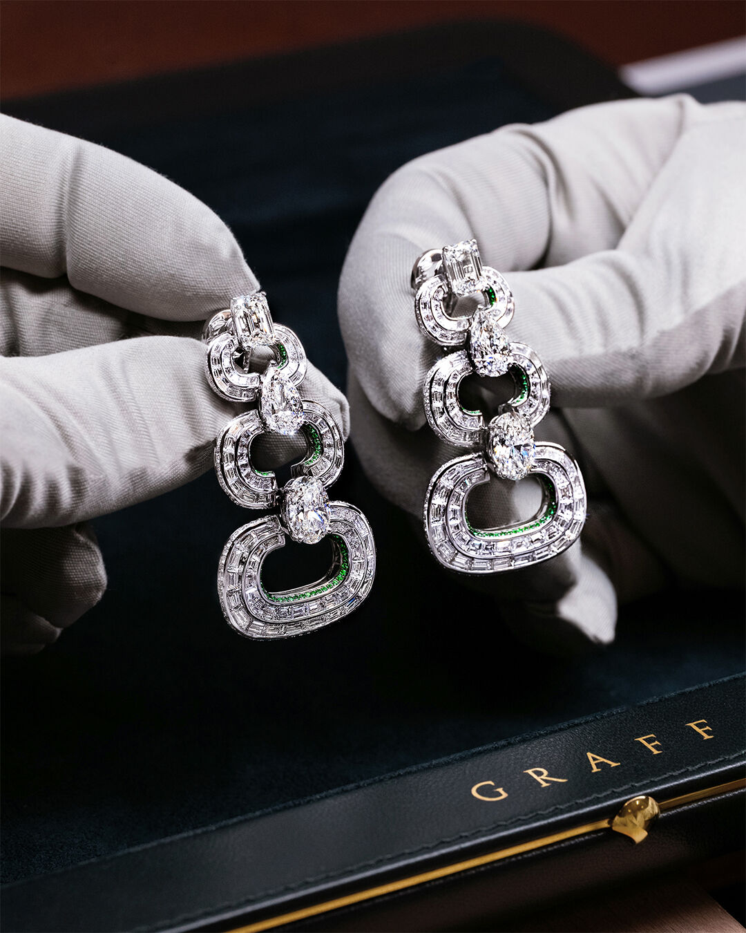 Image shows diamond and emerald high jewellery earrings in workshop