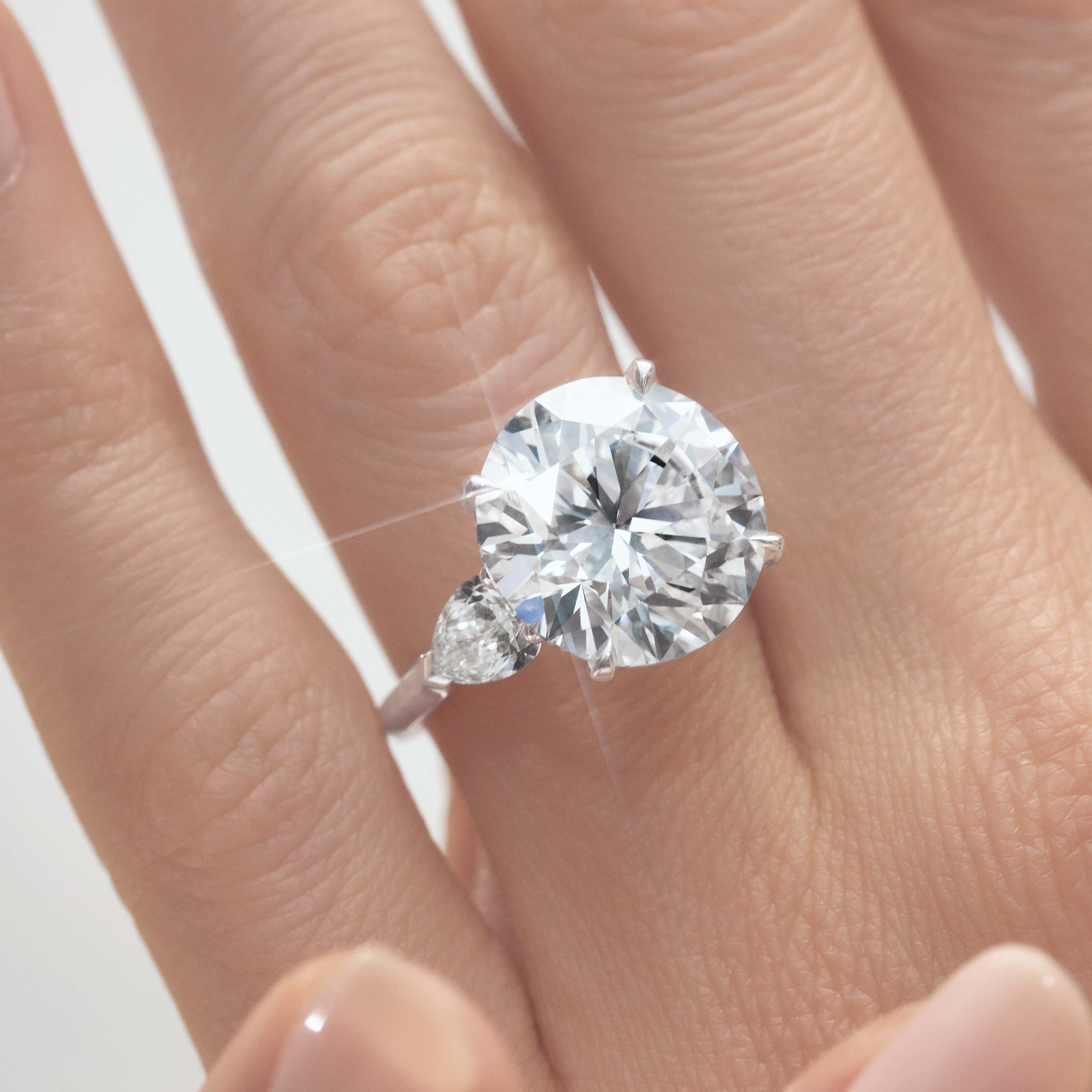 Close up of a models hand wearing a Graff round diamond engagement ring