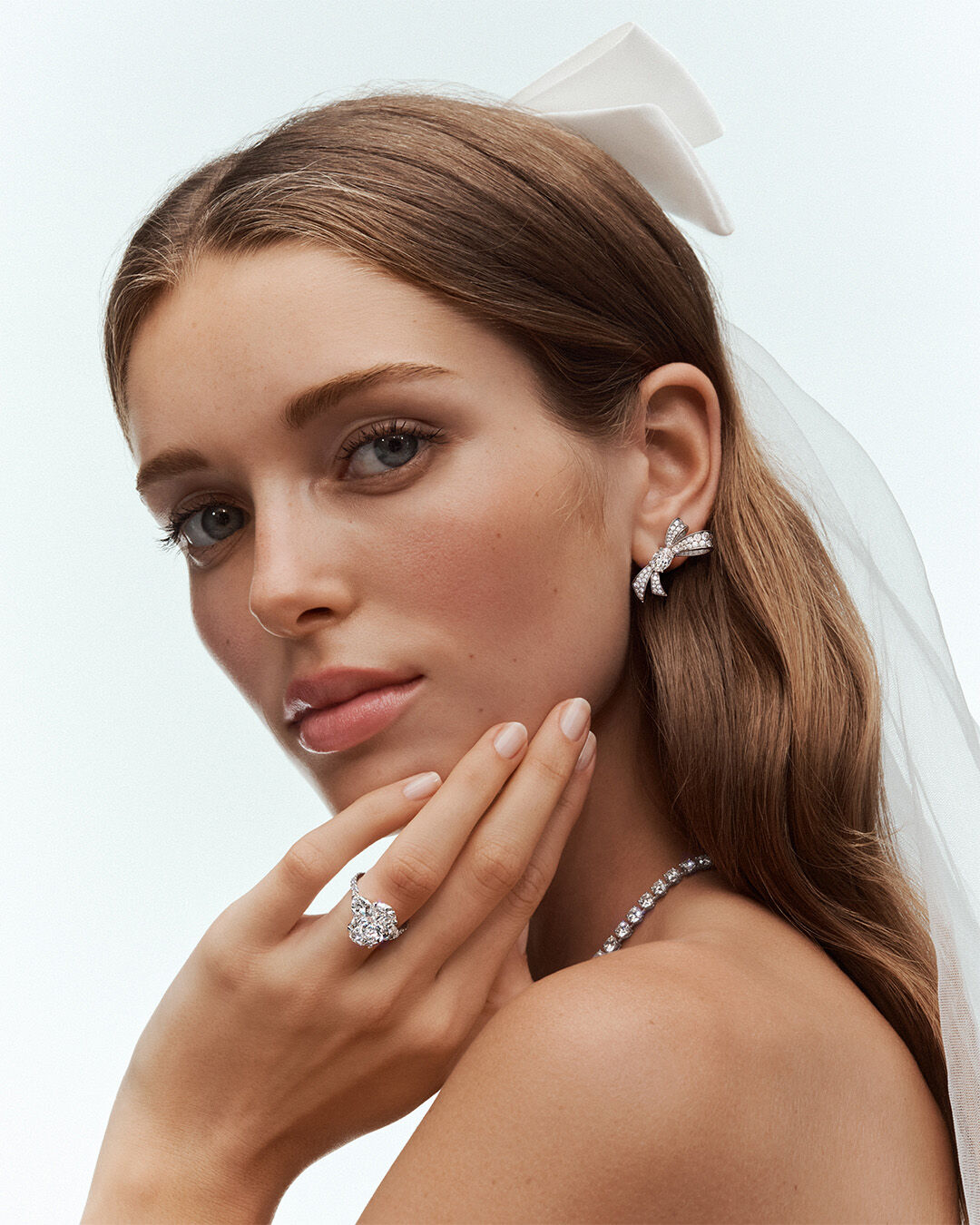 Image shows model wearing Graff Promise Oval Cut Diamond engagement ring, Tilda's Bow Earrings and round diamond necklace